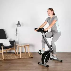 mujer entrenando sobre bicicleta estatica en casa